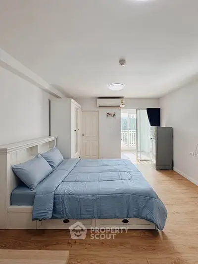 Spacious bedroom with modern decor and balcony access in a stylish apartment.