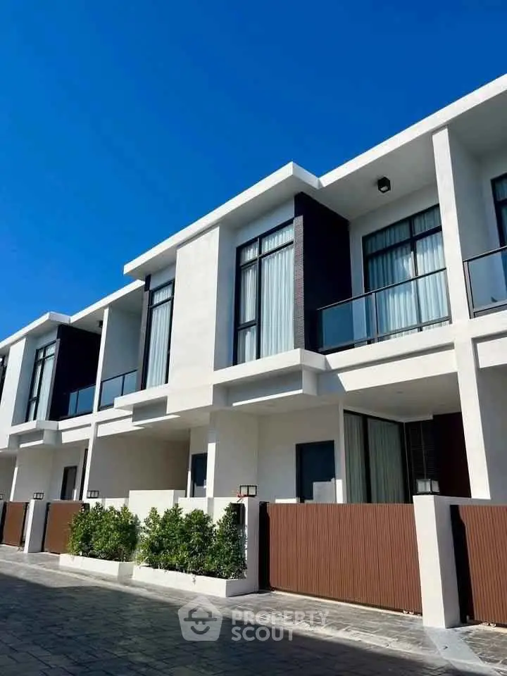 Modern townhouse exterior with sleek design and large windows under a clear blue sky.