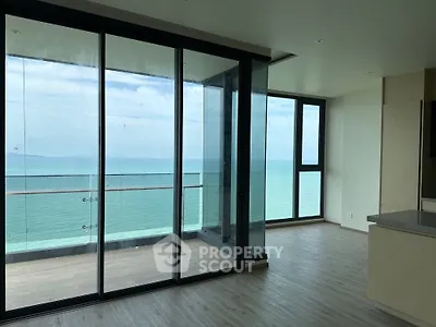 Stunning ocean view from modern apartment with floor-to-ceiling windows and spacious balcony.