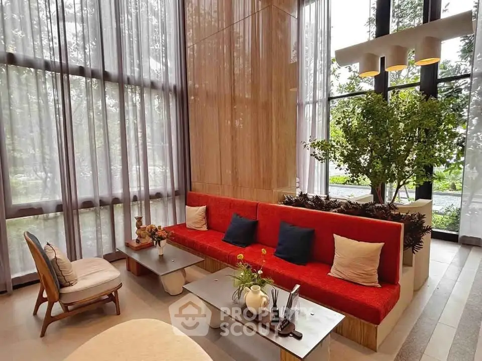 Luxurious modern living room with high ceilings, large windows, and elegant red sofa in a stylish apartment.