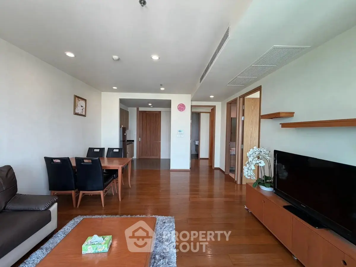 Spacious modern living room with wooden flooring and elegant furniture, perfect for family gatherings.