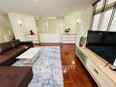 Spacious living room with modern decor and large TV, perfect for relaxation.