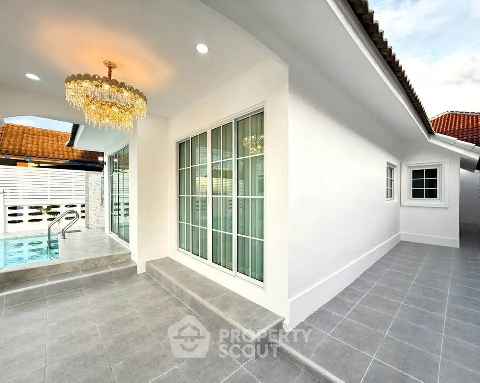 Elegant exterior with pool and chandelier, modern white facade and tiled flooring.