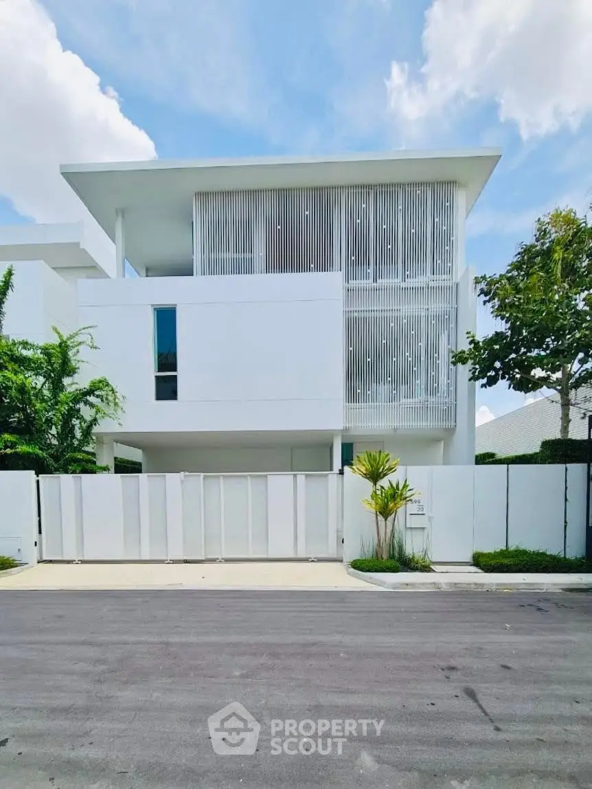 Modern minimalist white building with sleek lines and lush greenery, offering a serene urban living experience.