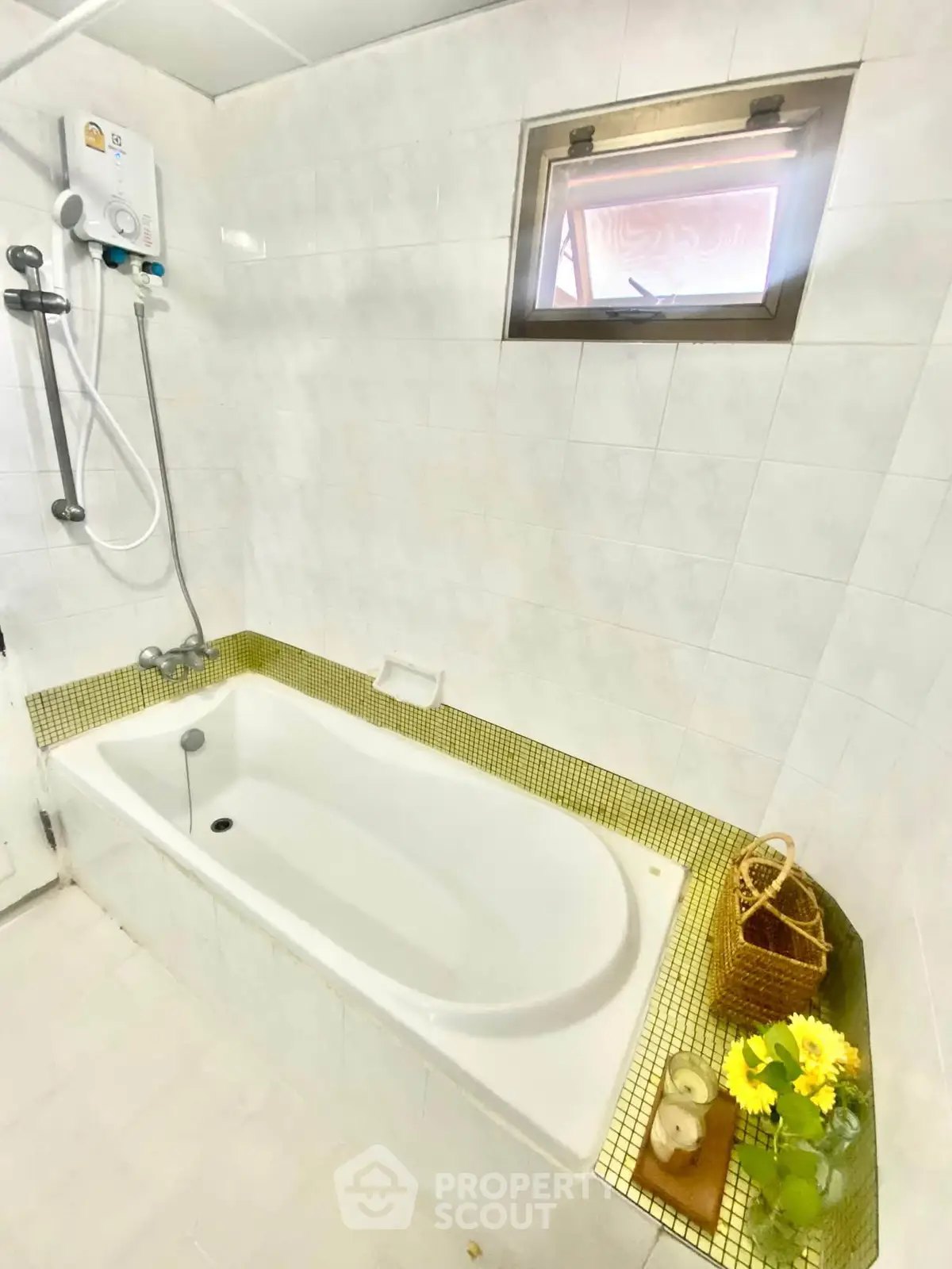 Bright bathroom with bathtub and window, featuring modern shower and decorative elements.
