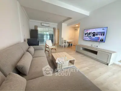 Spacious modern living room with cozy sofa and large TV, perfect for relaxation.
