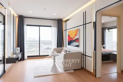 Modern living room with large windows and stylish decor in a high-rise apartment.