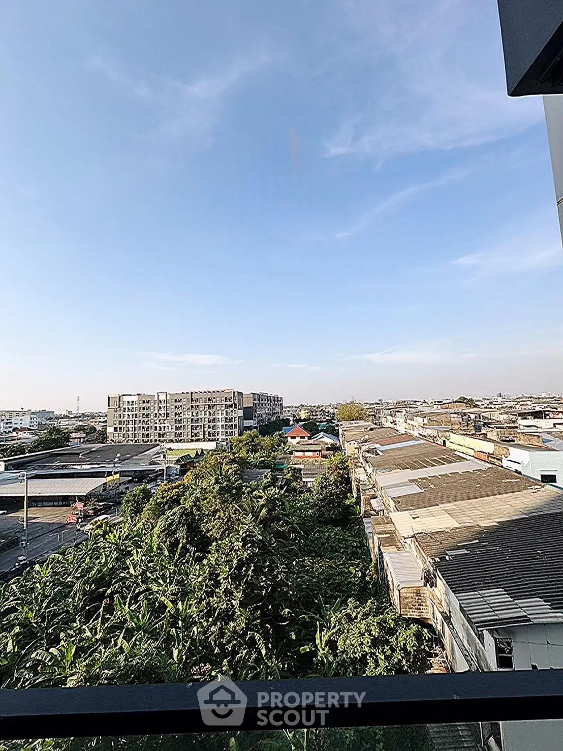 Stunning cityscape view from a high-rise balcony overlooking lush greenery and urban skyline.