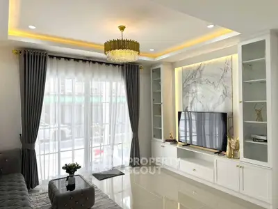 Elegant living room with modern decor, large TV, and luxurious chandelier.