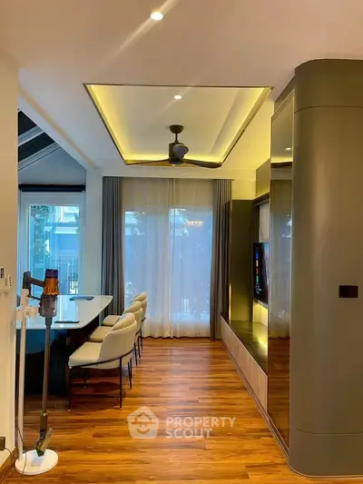 Modern living room with elegant dining area and stylish ceiling fan, featuring wooden flooring and large windows.