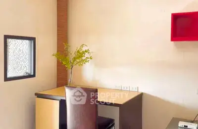 Modern study room with sleek desk and chair, featuring a small window and decorative plant.