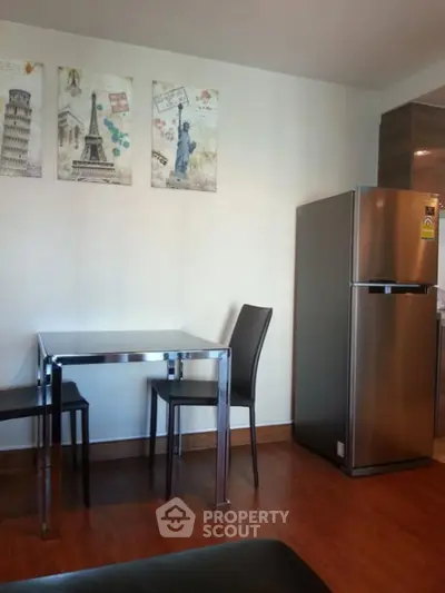 Modern dining area with sleek table, chairs, and stainless steel fridge in stylish apartment.