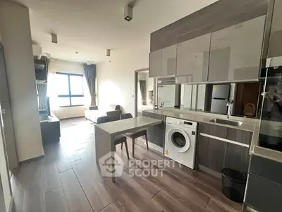 Modern open-layout kitchen with washing machine and dining area in bright apartment.