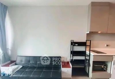 Modern studio apartment with sleek black sofa and compact kitchen area, perfect for urban living.