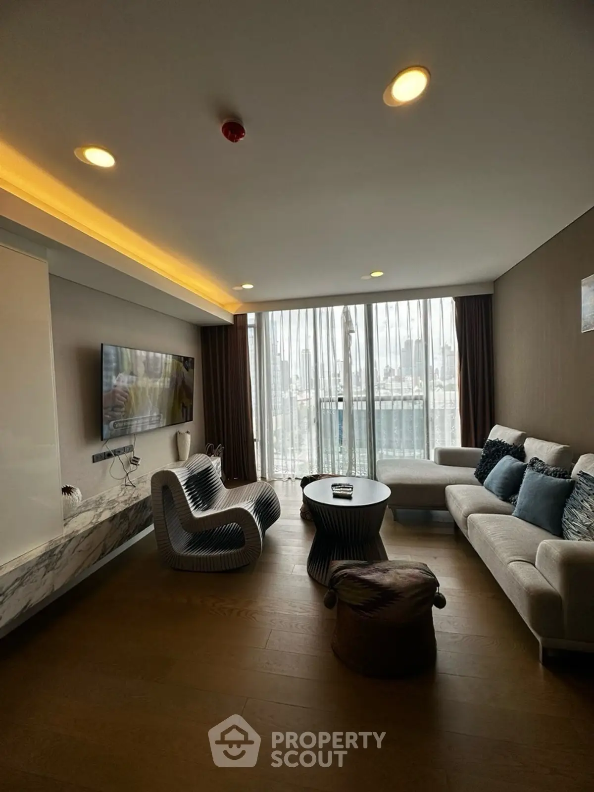 Modern living room with stylish furniture and city view through large windows.