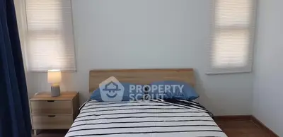 Cozy bedroom with modern wooden bed and nightstand, featuring striped bedding and soft lighting.