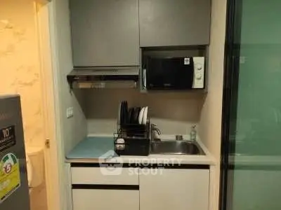 Compact kitchen with modern appliances and sleek cabinetry in a cozy apartment.