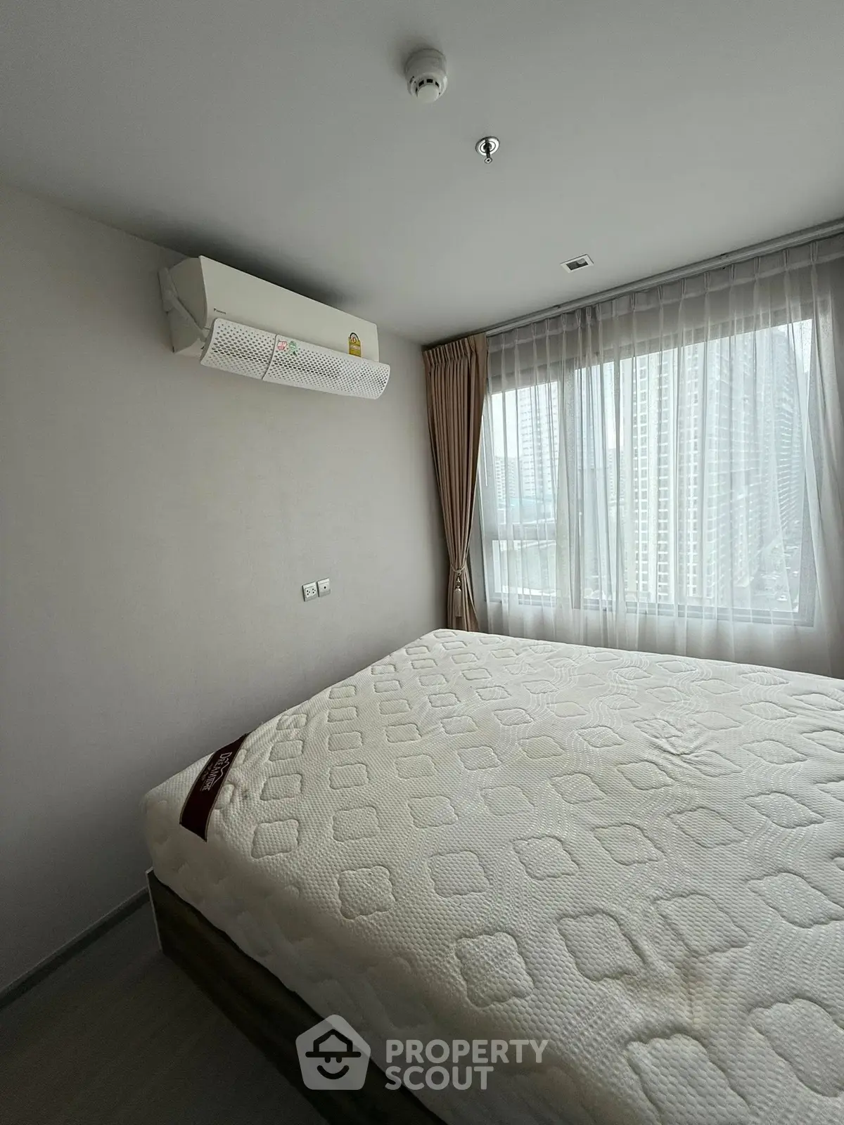 Modern bedroom with large window and air conditioning in urban apartment