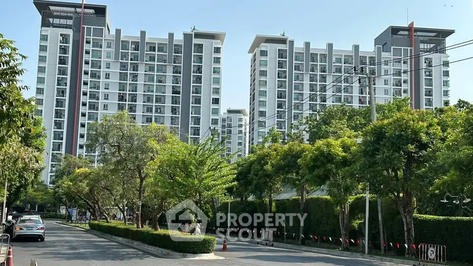 Modern high-rise residential buildings with lush greenery and clear blue sky.