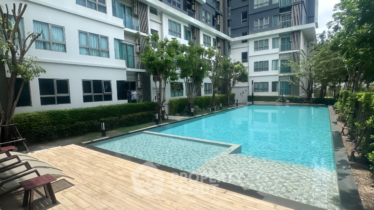 Modern apartment complex with a pristine swimming pool and lush greenery, offering a serene living environment.