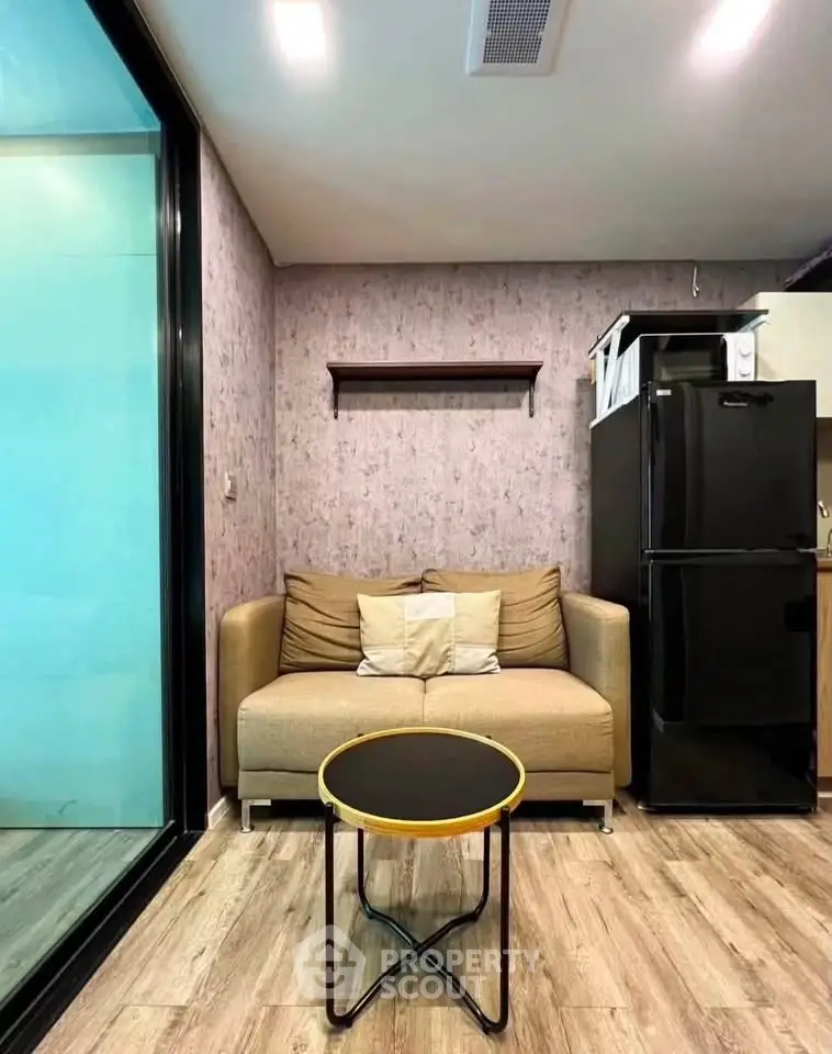 Modern living room with cozy sofa and sleek black refrigerator in stylish apartment.