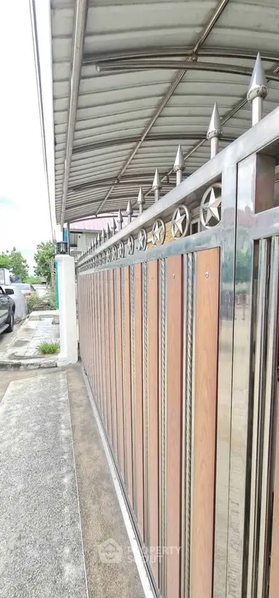 Modern gated entrance with stylish metal and wood design, showcasing security and elegance in residential property.