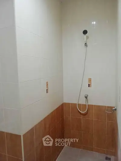Modern bathroom with tiled shower area and handheld showerhead.