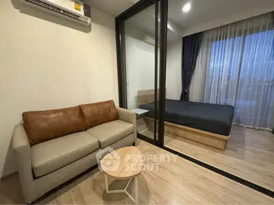 Modern apartment interior with cozy living room and bedroom separated by glass partition.