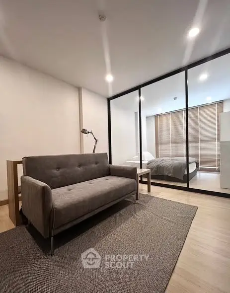 Modern studio apartment with glass partition, cozy sofa, and stylish bedroom.