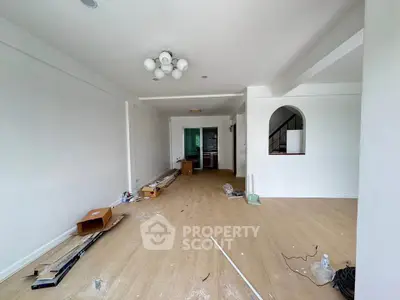Spacious living room under renovation with modern lighting and wooden flooring.