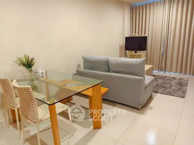 Modern living room with glass dining table and cozy sofa, perfect for relaxation.