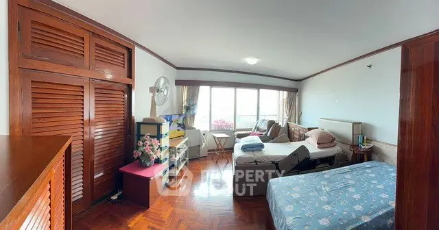 Spacious bedroom with wooden flooring and large windows offering natural light.