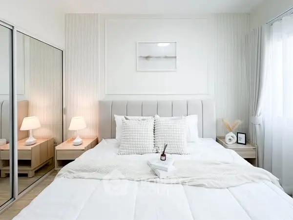 Elegant modern bedroom with cozy white bedding and mirrored closet doors.