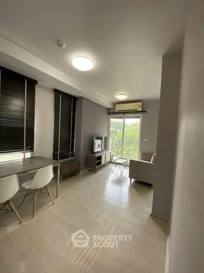 Modern living room with sleek furniture and large windows offering natural light and a balcony view.