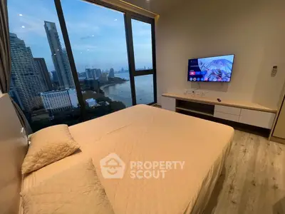 Luxurious bedroom with stunning city and river view, modern decor, and wall-mounted TV.