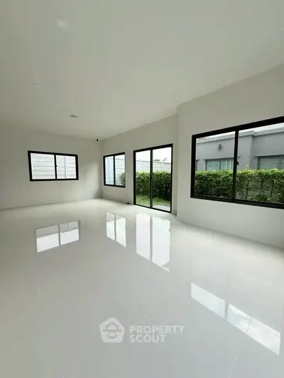 Spacious modern living room with large windows and garden view, perfect for natural light lovers.