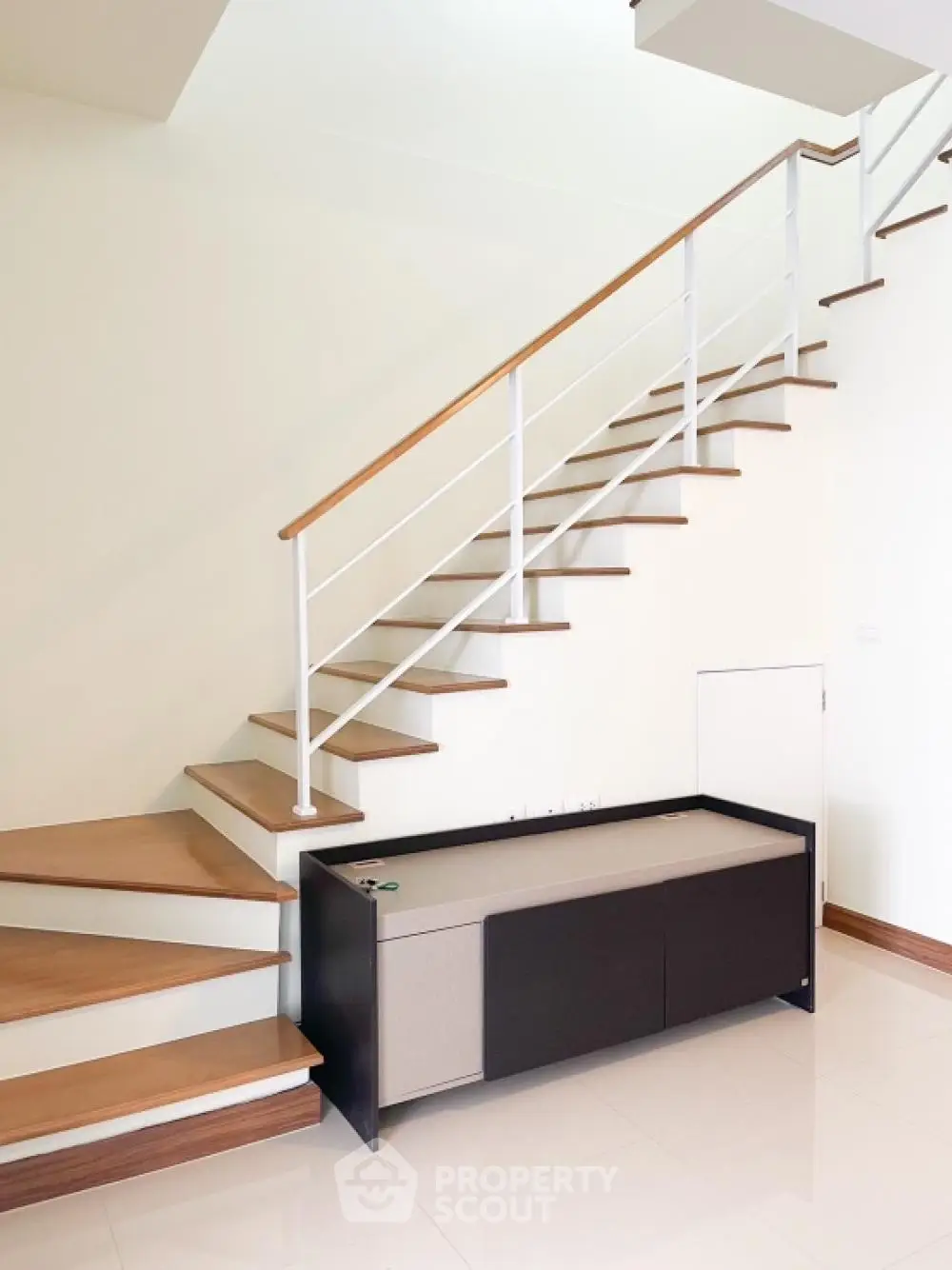 Elegant staircase with wooden steps and modern metal railings in a bright, spacious home interior, showcasing sophisticated design and architecture.
