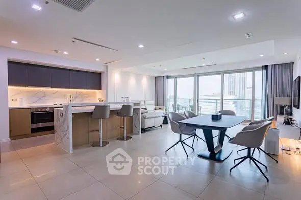 Spacious modern living room with open kitchen and city view balcony.