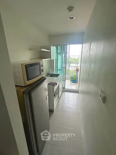 Compact kitchen with modern appliances and balcony view in cozy apartment