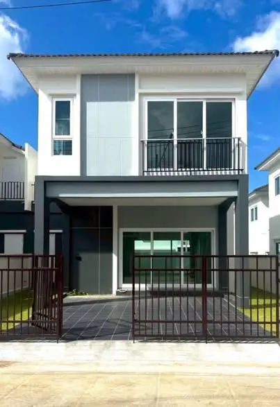 Modern two-story house with sleek design and balcony in a sunny neighborhood.