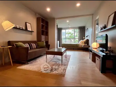 Modern living room with cozy decor and view into bedroom, featuring stylish furniture and warm lighting.