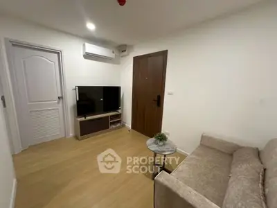 Cozy living room with modern decor, featuring a TV, air conditioning, and comfortable seating.