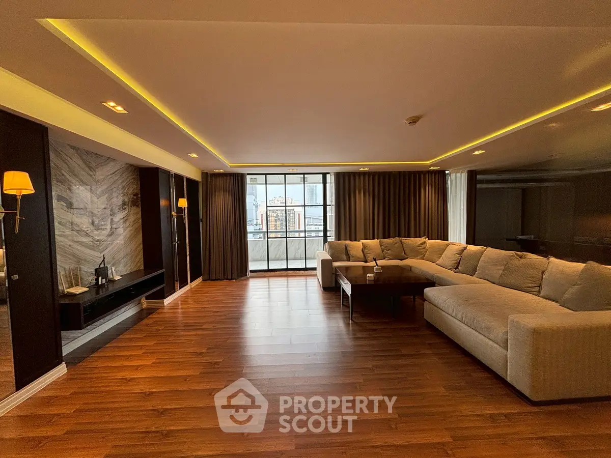 Spacious modern living room with large sectional sofa and city view.