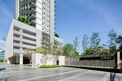 Modern high-rise building with sleek architecture and landscaped entrance in urban setting.