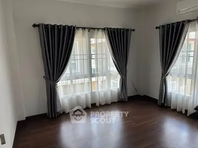 Spacious corner unit with elegant curtains and wooden flooring, perfect for natural light lovers.