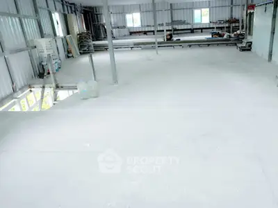 Spacious industrial warehouse interior with high ceilings and ample natural light.