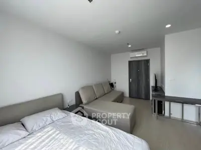 Modern studio apartment with cozy bed and stylish sofa in a bright, minimalist setting.