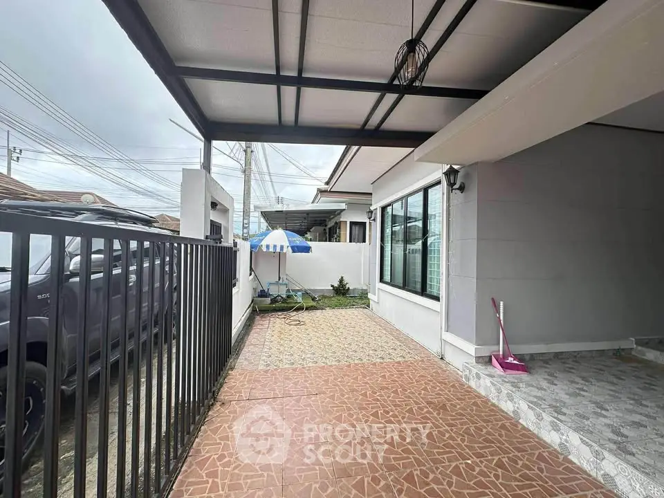 Charming home exterior with spacious tiled patio and covered parking area.