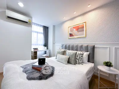 Modern bedroom with stylish decor and natural light, featuring a cozy bed and elegant wall art.