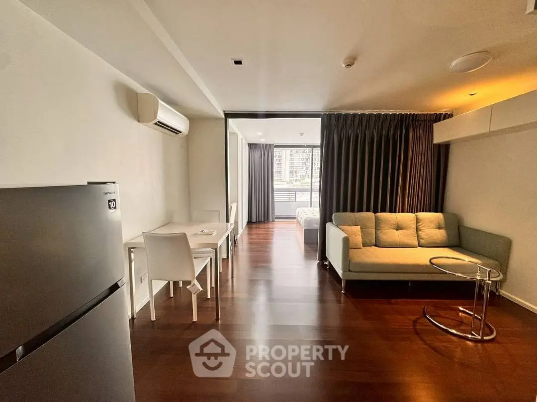 Modern open-plan living room with sleek furniture and wooden flooring.